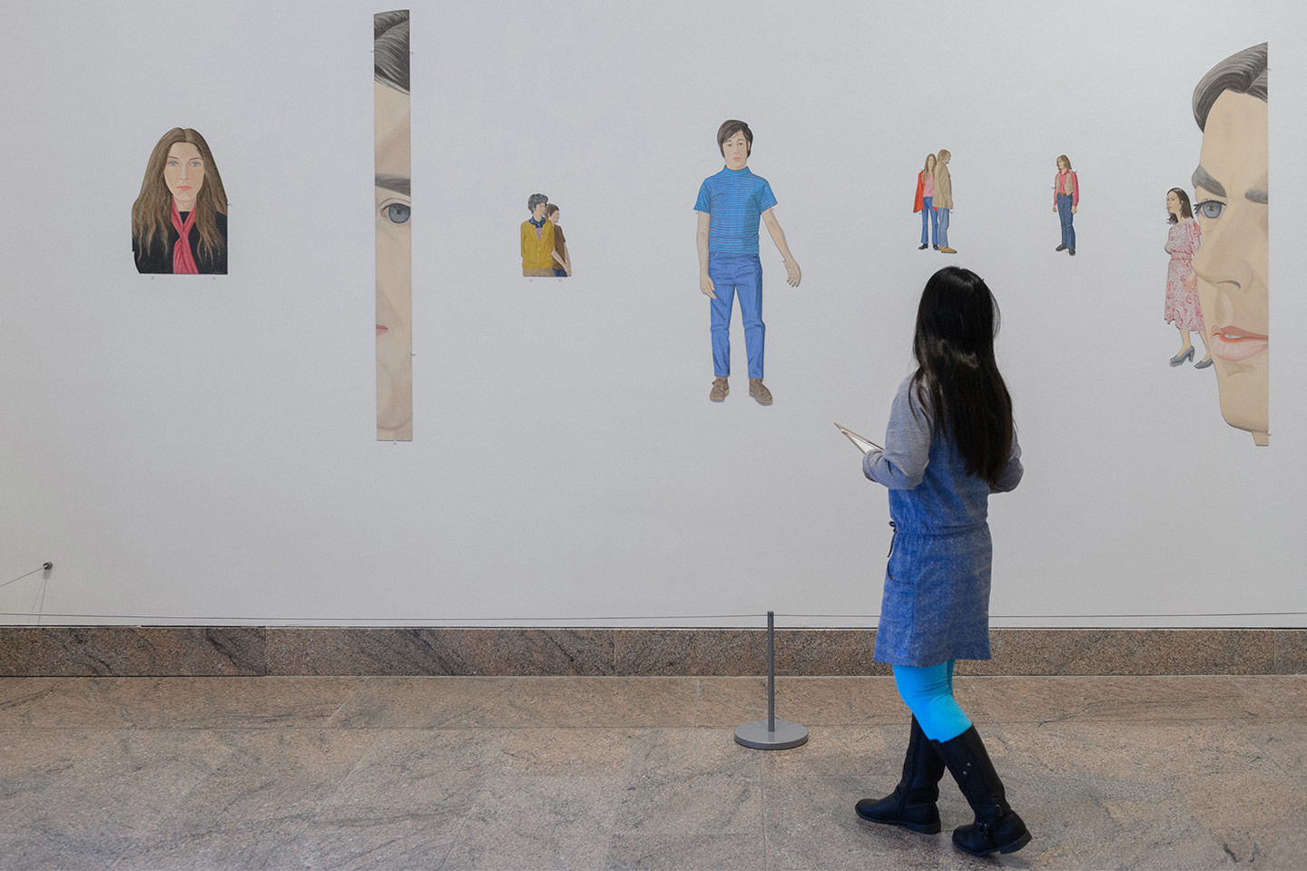 Young girl looks at a wall mural of naturalistic portraits of people